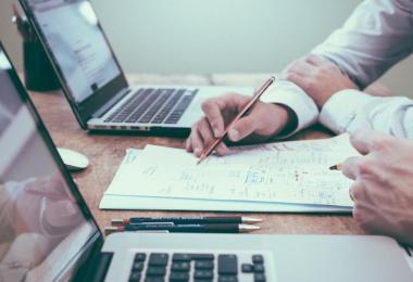 Business owners reviewing commercial insurance paperwork at a desk with laptops