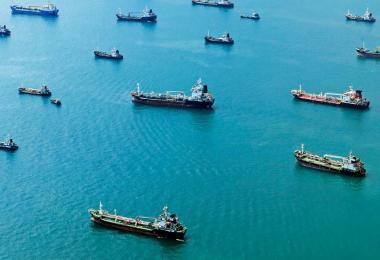 Cargo ships and tankers anchored offshore, the kind of sea transit a marine insurance policy is written to protect