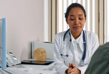 A doctor sitting with one patient at a consultation desk, the everyday care an individual medical insurance plan pays for