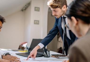 A business team reviewing benefit schedules together, the work of comparing one group medical insurance plan against another