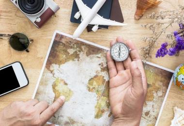 Travel planning flat lay with a world map, compass, passport and toy plane